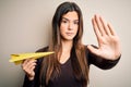 Young beautiful girl holding paper plane standing over isolated white background with open hand doing stop sign with serious and Royalty Free Stock Photo