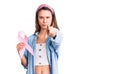 Young beautiful girl holding pink cancer ribbon pointing with finger to the camera and to you, confident gesture looking serious Royalty Free Stock Photo
