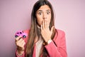 Young beautiful girl holding small car toy standing over isolated pink background cover mouth with hand shocked with shame for Royalty Free Stock Photo