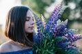Young beautiful girl holds a large bouquet of purple lupins in a flowering field. Blooming lupine flowers. environmentally Royalty Free Stock Photo