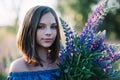 Young beautiful girl holds a large bouquet of purple lupins in a flowering field. Blooming lupine flowers. environmentally Royalty Free Stock Photo