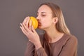 A young beautiful girl holds an orange in her hands and sniffs its smell Royalty Free Stock Photo