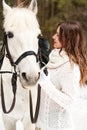 Young beautiful girl with a horse in the forest on a winter day