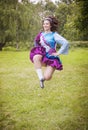 Young beautiful girl in irish dance dress jumping outdoor