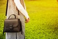 Young beautiful girl in jeans with bag on shoulder walks in green park in spring