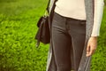 Young beautiful girl in jeans with bag on shoulder walks in green park