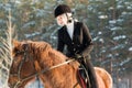 Young beautiful girl jockey riding a horse in winter forest Royalty Free Stock Photo