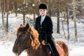 Young beautiful girl jockey riding a horse in winter forest Royalty Free Stock Photo