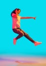 Young beautiful girl jumping isolated on blue background in neon light Royalty Free Stock Photo