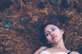 Young beautiful girl laying on the forest floor, with hair tangled in small branches that felled from pine trees, fashion concept