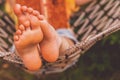 Young beautiful girl lies in a hammock and reads a book. Rest, summer vacation, leisure time concept. Selective focus on feets.