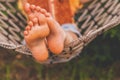 A young beautiful girl lies in a hammock and reads a book. Selective focus on feets. Horizontal image