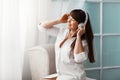 Young beautiful girl listening to music with headphones. The girl is enjoying the music sitting by the window. Rest, relaxation Royalty Free Stock Photo