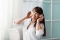 Young beautiful girl listening to music with headphones. The girl is enjoying the music sitting by the window. Rest, relaxation Royalty Free Stock Photo