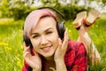 Young beautiful girl listening to music on headphones and lies on a green grass and dandelions Royalty Free Stock Photo