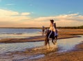 A young beautiful girl in a long dress rides a horse on the beach of the Gulf of Finland Royalty Free Stock Photo