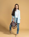 Young beautiful girl with long flowing hair in a white shirt and blue jacket posing on a pastel orange studio background Royalty Free Stock Photo