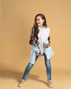 Young beautiful girl with long flowing hair in a white shirt and blue jacket posing on a pastel orange studio background Royalty Free Stock Photo