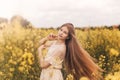 Young beautiful girl with long hair flying in the wind against the background of rapeseed field. Breeze playing with girl`s hair