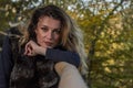 Young beautiful girl with long hair, in a fur jacket, stands on a wooden railing on a bright sunny day while walking in the autumn Royalty Free Stock Photo