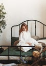 A young beautiful girl with long hair sits on a bed with pillows. Woman enjoying morning awakening . The concept of home coziness Royalty Free Stock Photo