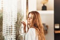 Young beautiful girl with long hair stands near the mirror in the morning in the bedroom