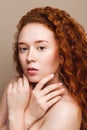 young beautiful girl with long red curly hair looks at the camera. The concept of natural beauty. Close-up shot in the studio on a Royalty Free Stock Photo