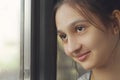 A young beautiful girl looks out the window and smiles. Royalty Free Stock Photo