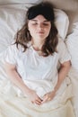 Young beautiful girl lying in comfortable bed wearing sleep mask in the morning at cozy room. Concept of rest at home Royalty Free Stock Photo