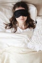 Young beautiful girl lying in comfortable bed wearing sleep mask in the morning at cozy room. Concept of rest at home Royalty Free Stock Photo