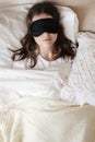 Young beautiful girl lying in comfortable bed wearing sleep mask in the morning at cozy room. Concept of rest at home Royalty Free Stock Photo