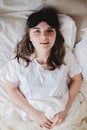 Young beautiful girl lying in comfortable bed wearing sleep mask in the morning at cozy room. Concept of rest at home Royalty Free Stock Photo