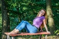 Young beautiful girl model in jeans and a T-shirt with long blond hair and sad smiles pensively posing for a walk in the autumn pa Royalty Free Stock Photo