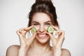 Young beautiful girl with perfect clean skin smiling looking at camera holding cucumber slices over white background Royalty Free Stock Photo