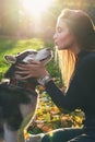 Young beautiful girl playing with her cute husky dog pet in autumn park covered with red and yellow fallen leaves Royalty Free Stock Photo