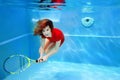 Young beautiful girl playing tennis underwater in the swimming pool