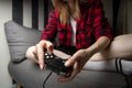 Young girl plays on the console, she sits at home on the couch and holds the joystick, close-up of the device