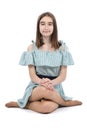 A young beautiful girl in a polka dot dress sits on the floor, isolated on a white background Royalty Free Stock Photo
