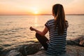 Young beautiful girl practicing yoga and meditation on the rocks next to the sea at sunset. Sport. Yoga. Meditation Royalty Free Stock Photo