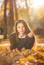 Young brunette girl in a purple sweater lies on fallen autumn leaves Royalty Free Stock Photo