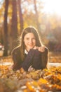 Young brunette girl in a purple sweater lies on fallen autumn leaves Royalty Free Stock Photo