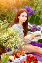 Young beautiful girl reads a book in nature sitting, where there are a lot of flowers and grass. Nature and relaxation. Leisure