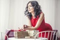 Young beautiful girl in red dress with books on the table