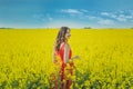 Young beautiful girl in a red dress close up in the middle of the yellow field with the radish flowers closeup Royalty Free Stock Photo