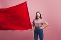 Young and beautiful girl with a red flag on a pink background. A socially active woman, to protest and fight for rights