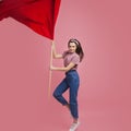 Young and beautiful girl with a red flag on a pink background. A socially active woman, to protest and fight for rights