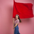 Young and beautiful girl with a red flag on a pink background. A socially active woman, to protest and fight for rights