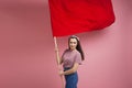 Young and beautiful girl with a red flag on a pink background. A socially active woman, to protest and fight for rights