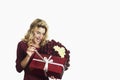 Young beautiful girl with a red gift with a white bow and flowers in her hands rejoices on an isolated white background. Valentine Royalty Free Stock Photo