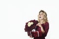 Young beautiful girl with a red gift with a white bow and flowers in her hands rejoices on an isolated white background. Valentine